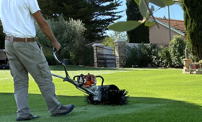 professionnel du gazon qui entretien son terrain avec une machine